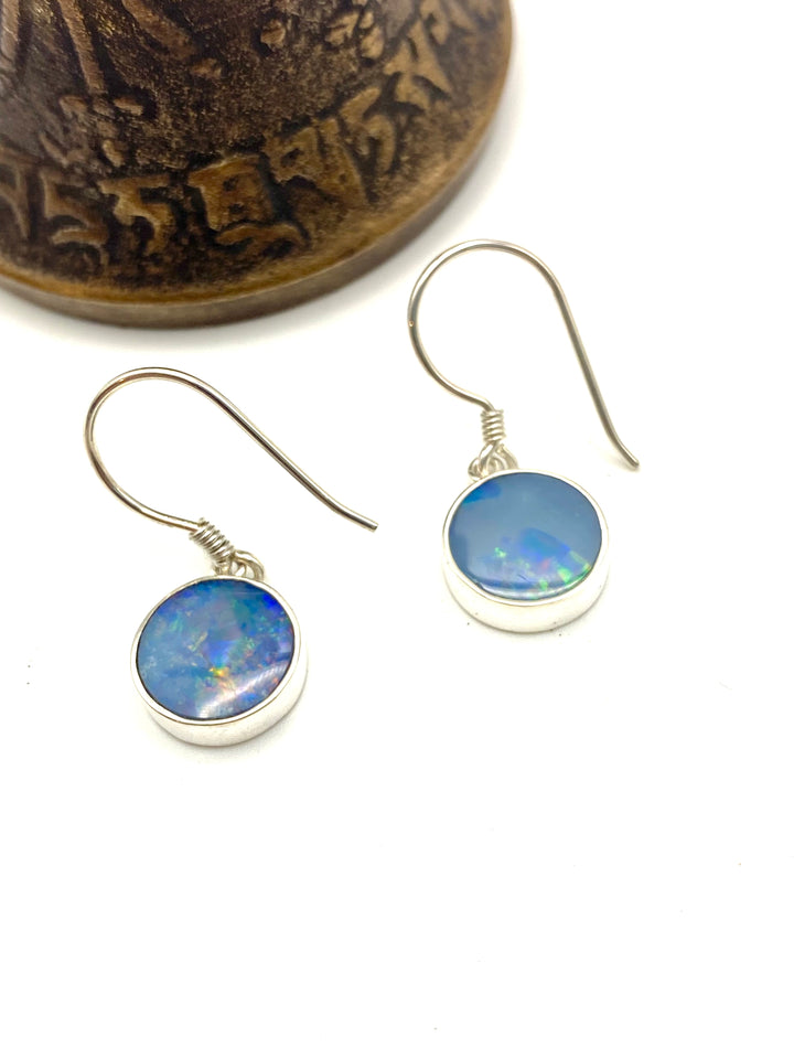 Full silhouette view of round blue opal drop earrings against a plain background showing simple bezel setting and drop length