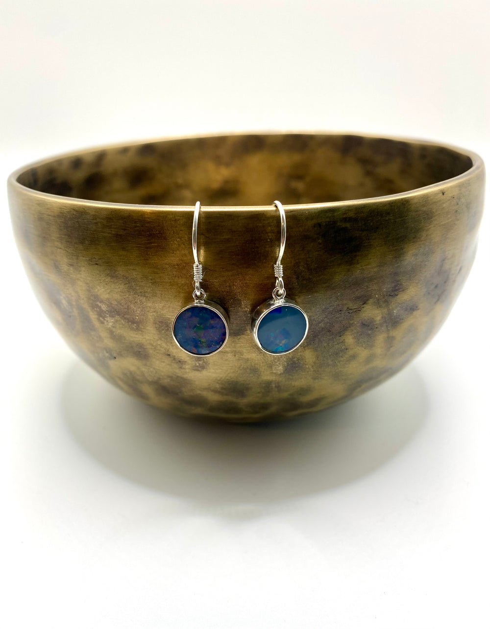 Blue opal drop earrings photographed beside a brass singing bowl showing full drop length and earring scale