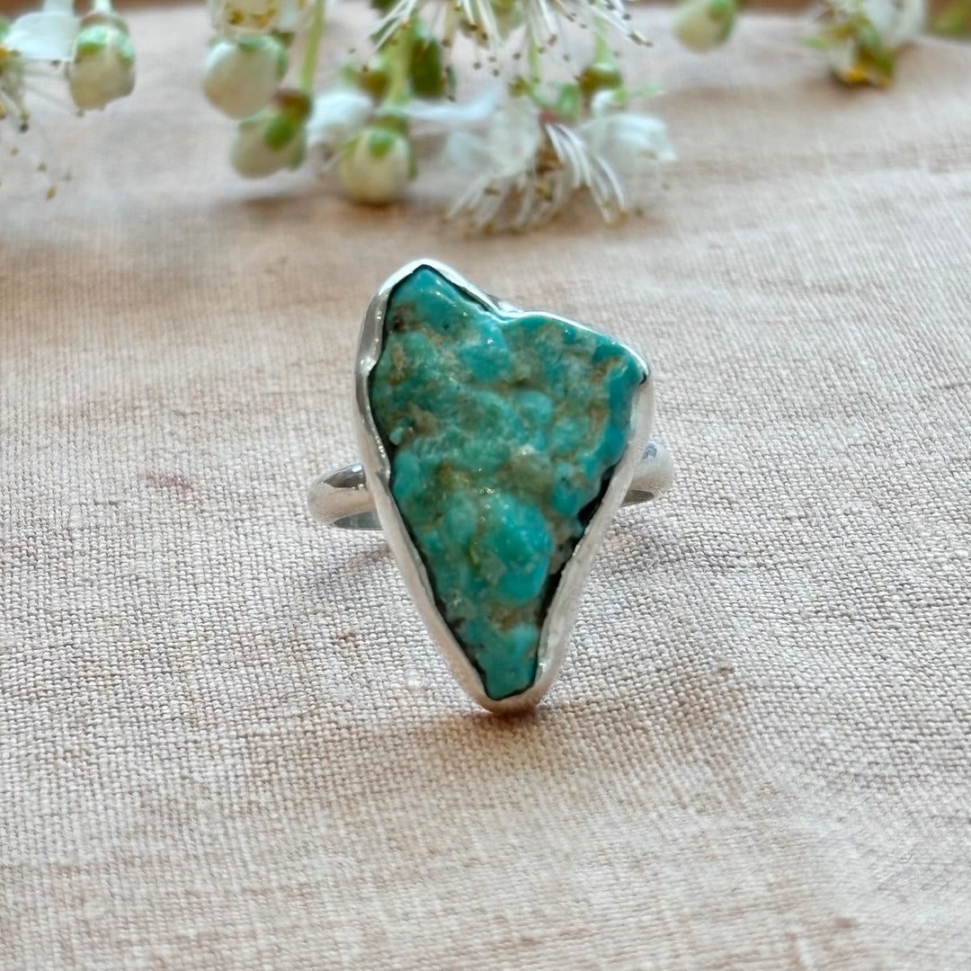 Raw turquoise stone set in a handmade sterling silver freeform ring, showing natural blue-green tones and earthy matrix pattern